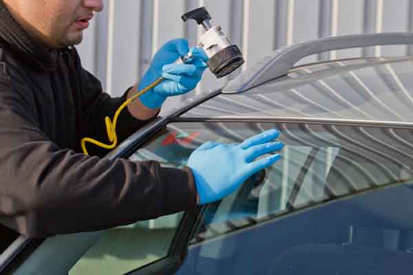 Professional auto glass technician repairing chip in windshield