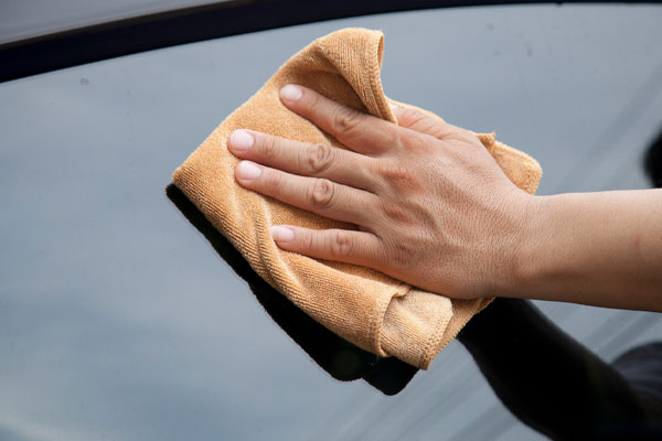 image of car owner cleaning auto glass