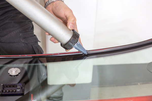 auto glass technician repairing windshield seal