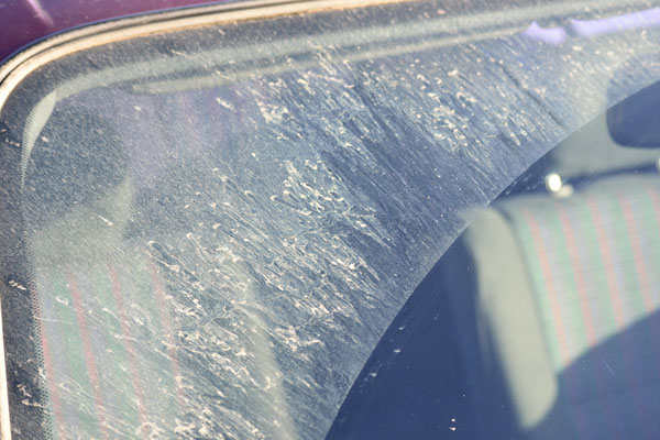 image of a windshield covered with sand and pits