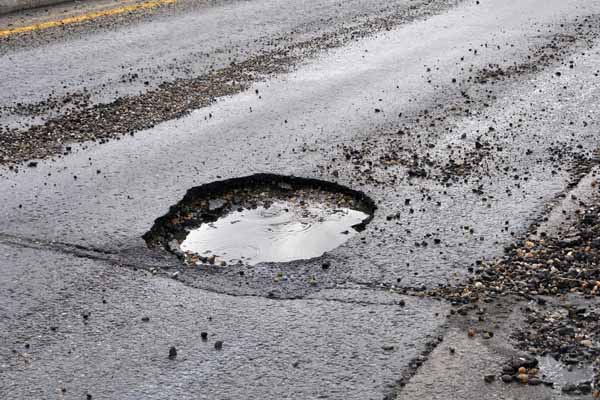 image of pothole in road depicting car auto glass cracks