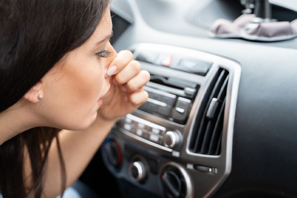 image of a driver plugging nose due to bad odor from car window leakage