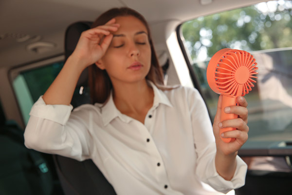 image of a woman suffering from heat in car depicting how to keep car cool in the summer