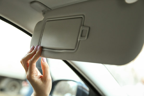 image of car owner using car visor to keep car cool