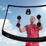 mechanic holding vehicle windshield